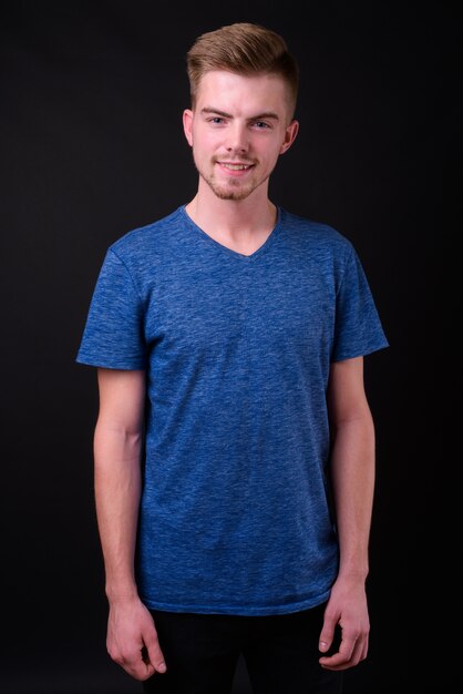 Photo studio shot of young handsome man against black background