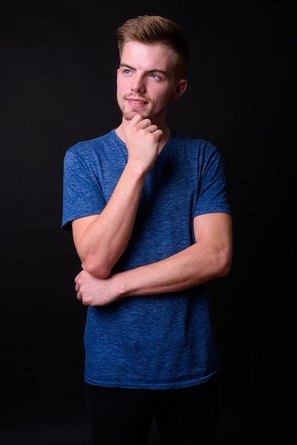 Studio shot of young handsome man against black background