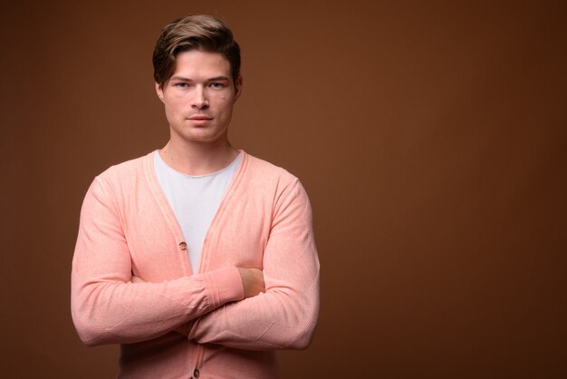 Studio shot of young handsome man against brown background