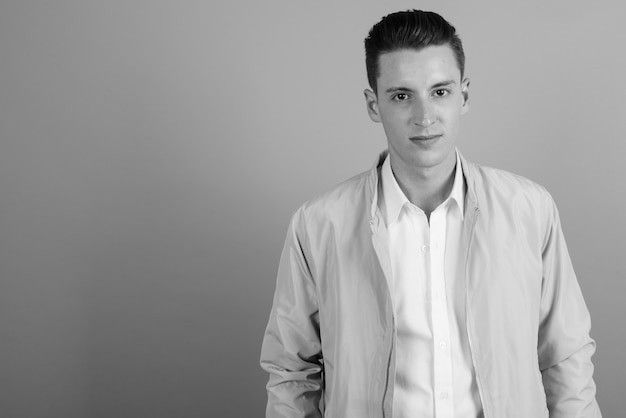 Studio shot of young handsome man against gray background in black and white