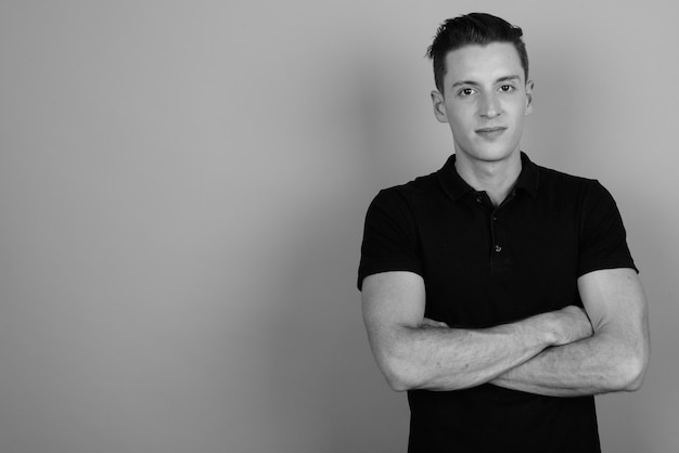 Studio shot of young handsome man against gray background in black and white