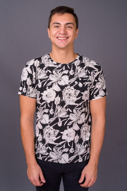 Studio shot of young handsome man against gray background