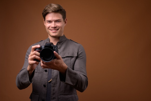 Studio shot of young handsome man as photographer with camera