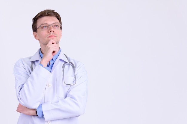 Studio shot of young handsome man doctor with eyeglasses against white