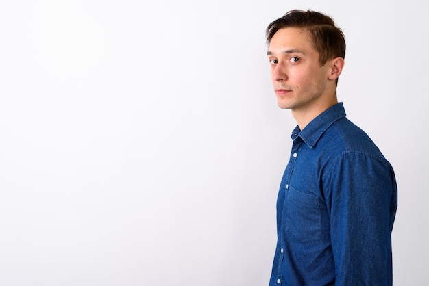 Studio shot of young handsome man looking at camera against whit