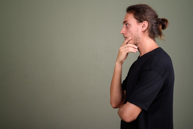 Studio shot of young handsome man wearing black shirt against colored background