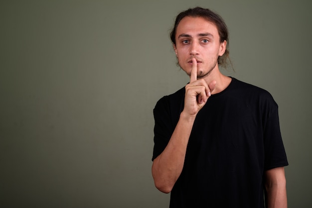 Studio shot of young handsome man wearing black shirt against colored background