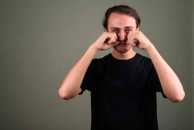 Studio shot of young handsome man wearing black shirt against colored background