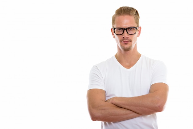 Studio shot of young handsome man wearing eyeglasses with arms crossed