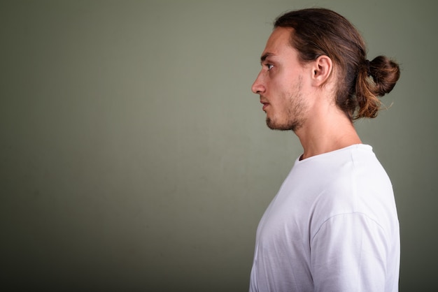 Foto studio shot di giovane uomo bello che indossa una camicia bianca su sfondo colorato