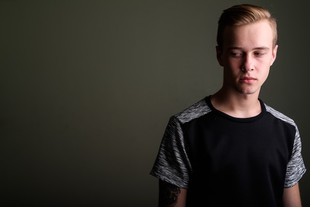 Studio shot of young handsome man with blond hair against colored background