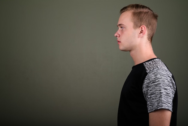 Photo studio shot of young handsome man with blond hair against colored background