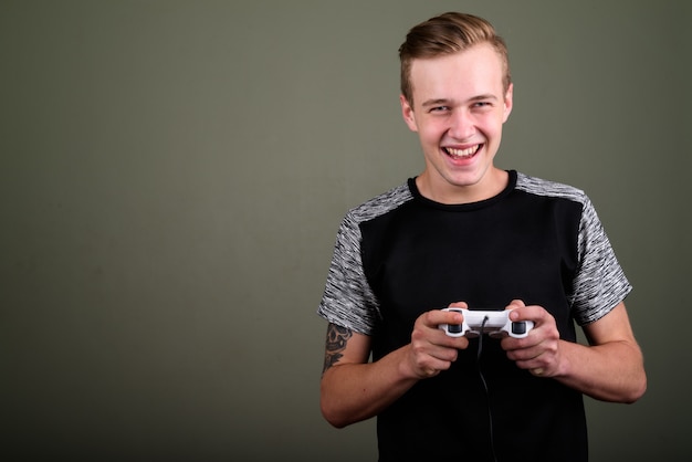 Studio shot of young handsome man with blond hair against colored background