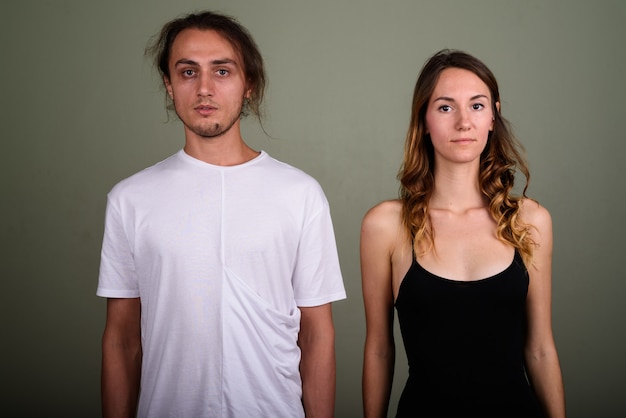 Studio shot of young handsome man and young beautiful woman together against colored background