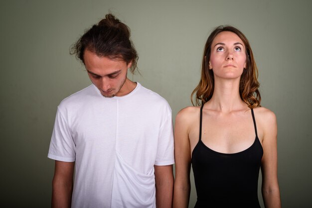 Studio shot of young handsome man and young beautiful woman together against colored background