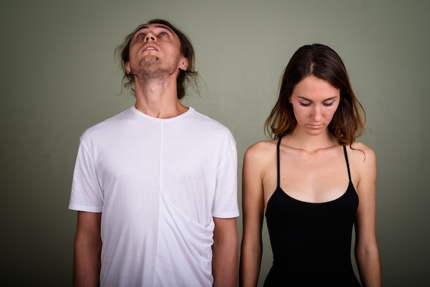 Studio shot of young handsome man and young beautiful woman together against colored background