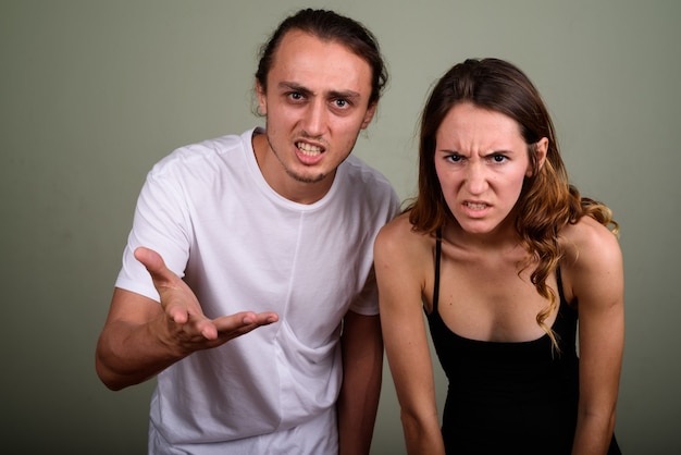 Studio shot of young handsome man and young beautiful woman together against colored background