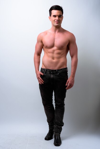 Studio shot of young handsome muscular man shirtless against white background