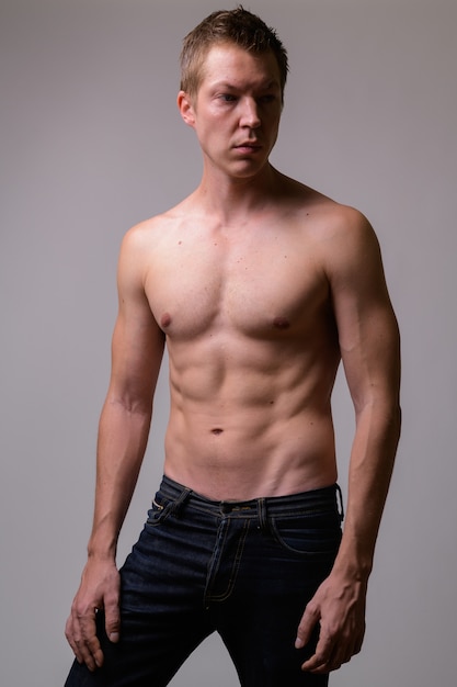 Studio shot of young handsome muscular shirtless man against white background