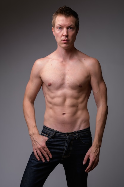 Studio shot of young handsome muscular shirtless man against white background