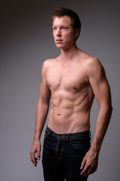 白い背景の若いハンサムな筋肉の上半身裸の男のスタジオショット