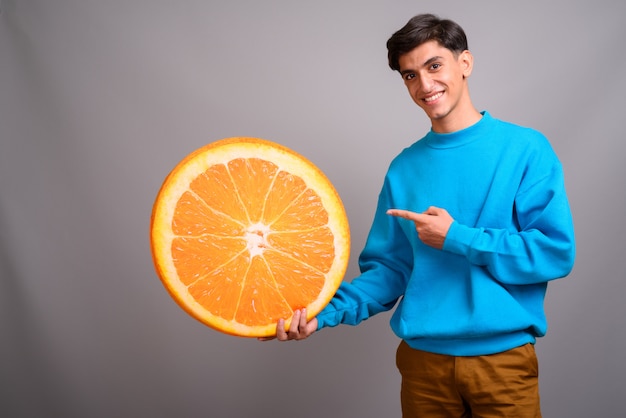 Studio shot of young handsome Persian teenage boy against gray background