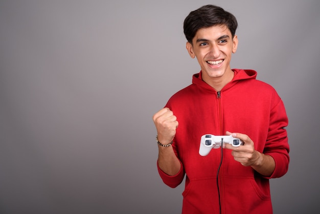 Studio shot of young handsome Persian teenage boy against gray background