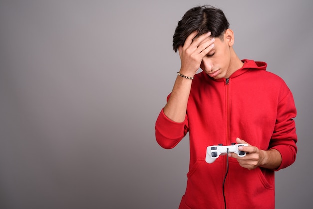 Studio shot of young handsome persian teenage boy against gray background