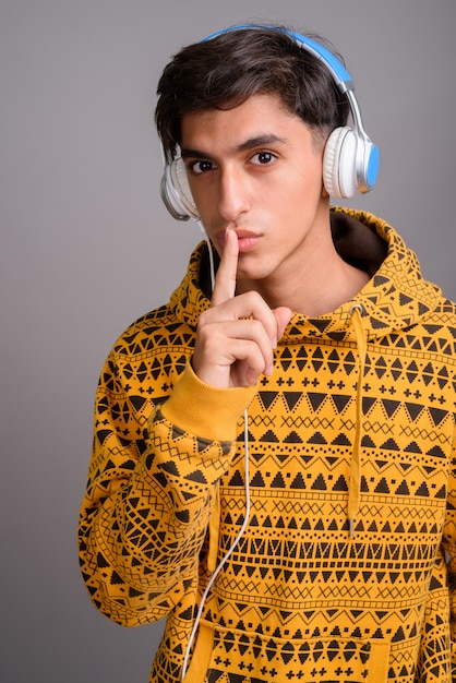 Studio shot of young handsome Persian teenage boy against gray background