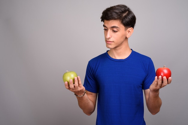 Studio shot of young handsome Persian teenage boy against gray background