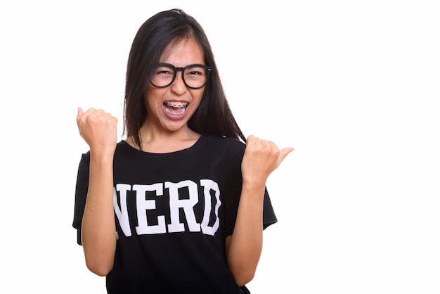 Studio shot of young happy Asian teenage nerd girl smiling