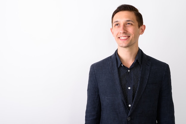 Studio shot of young happy businessman smiling while thinking an