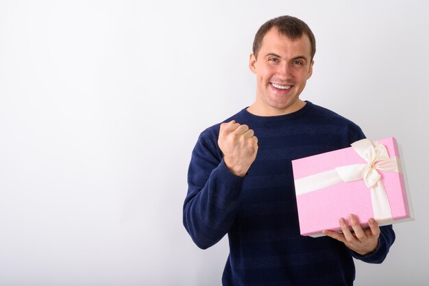 Studio shot of young happy muscular man smiling while holding gi