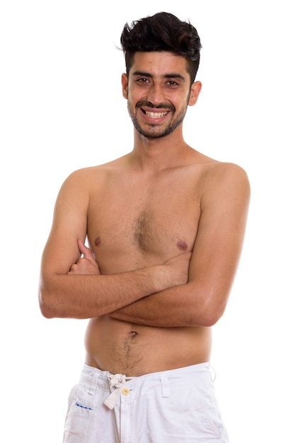 Studio shot of young happy Persian man smiling while standing sh