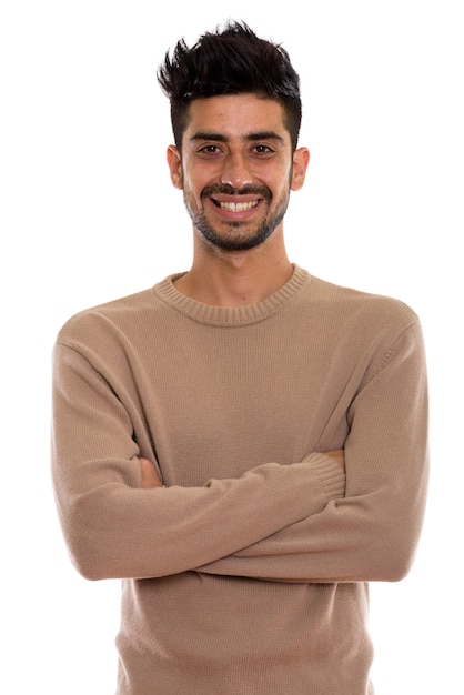 Studio shot of young happy Persian man smiling with arms crossed