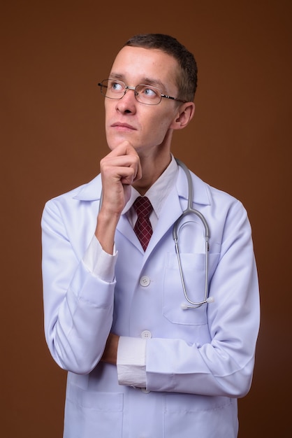 Studio shot of young man doctor on brown