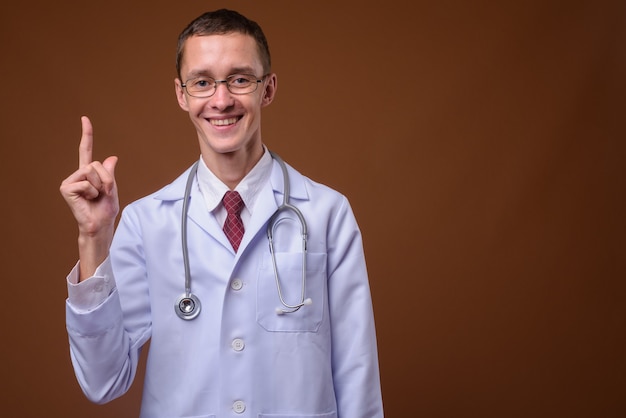 Studio shot of young man doctor on brown