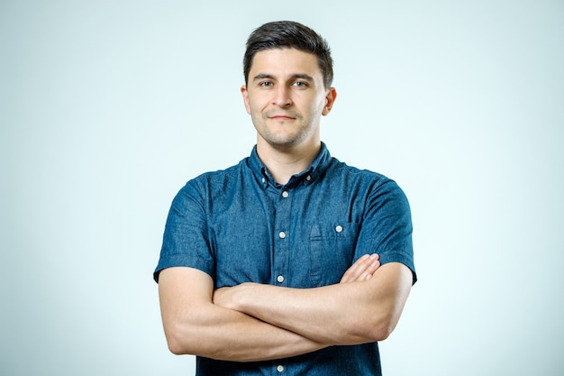 Studio shot of young man with crossed hands looking at the camera