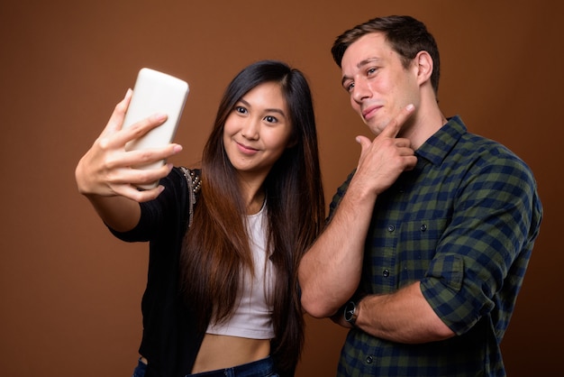 Studio shot of young multi-ethnic couple on brown wall