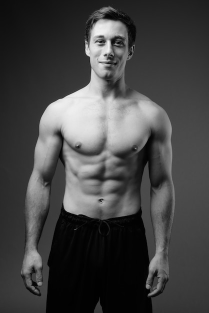 Studio shot of young muscular handsome man shirtless in black and white