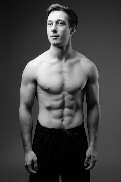 Studio shot of young muscular handsome man shirtless in black and white