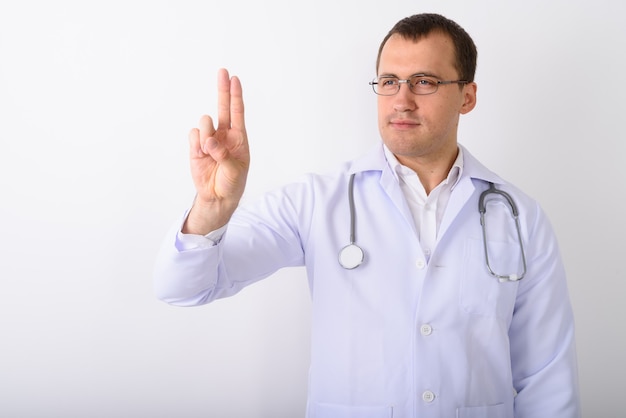 Studio shot of young muscular man doctor thinking while touching