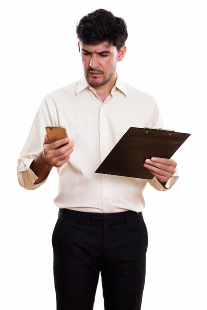 Studio shot of young Persian businessman holding clipboard while