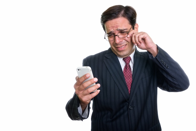 Studio shot of young Persian businessman using mobile phone