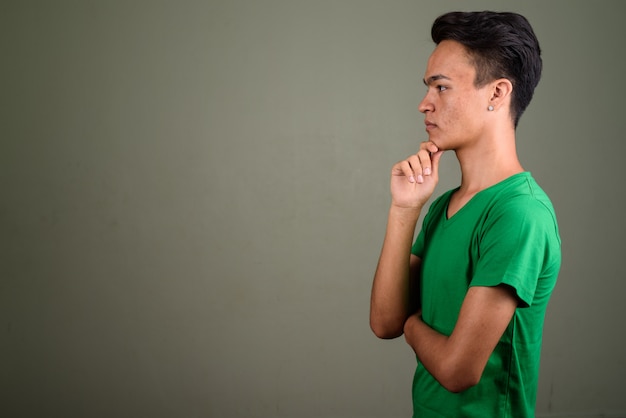 Studio shot of young teenage man wearing green shirt against colored