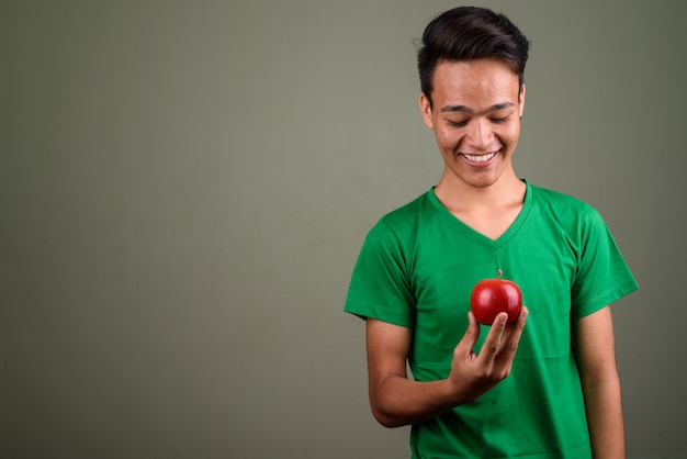 Studio shot of young teenage man wearing green shirt against colored