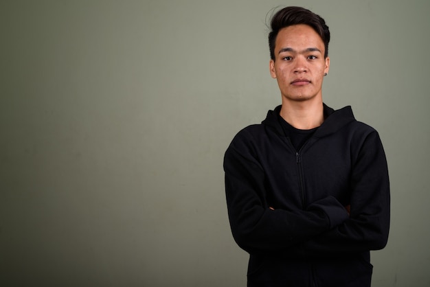 Studio shot of young teenage man wearing hoodie against colored