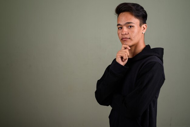 Studio shot of young teenage man wearing hoodie against colored