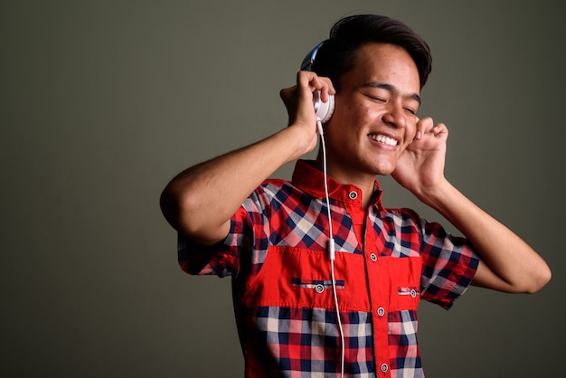 Photo studio shot of young teenage man wearing red checkered shirt against colored