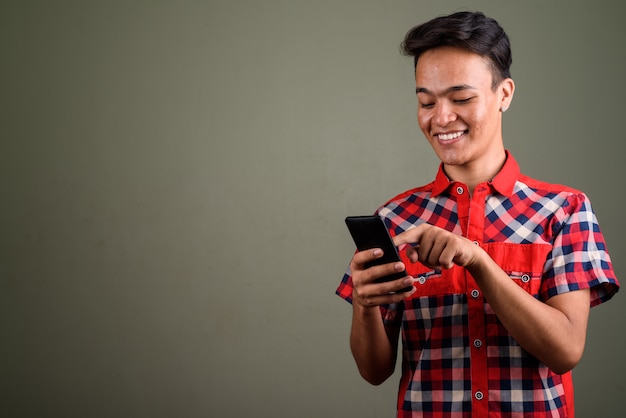 Studio shot of young teenage man wearing red checkered shirt against colored